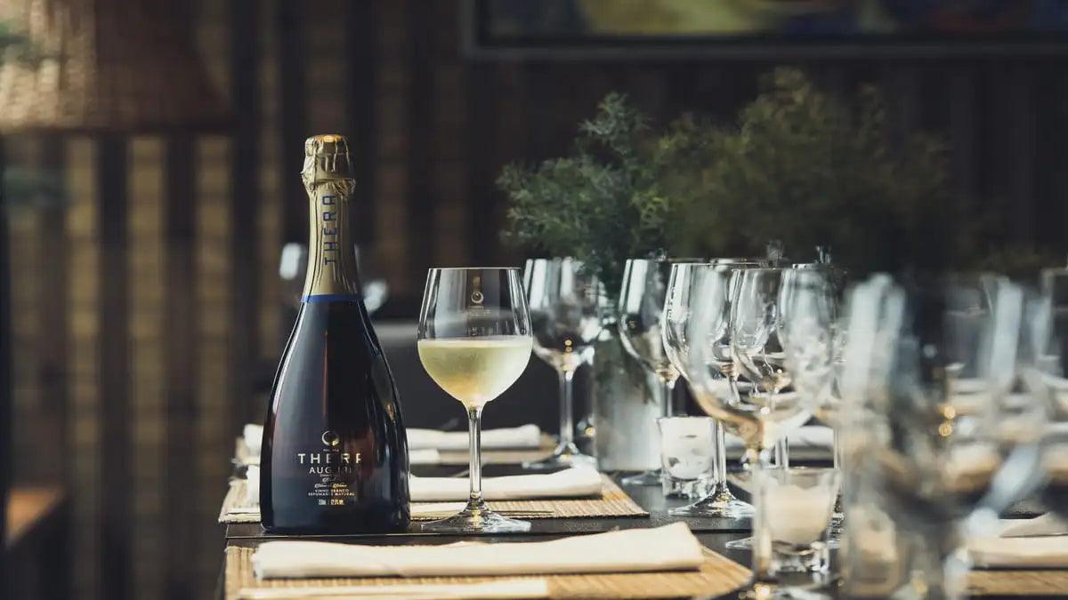 a imagem mostra uma mesa com um rótulo da vinícola thera e várias taças.